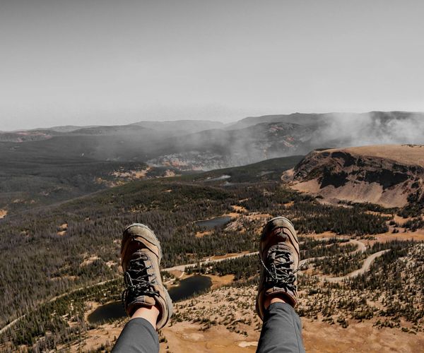 Person meditating on a beautiful viewpoint during a trip.